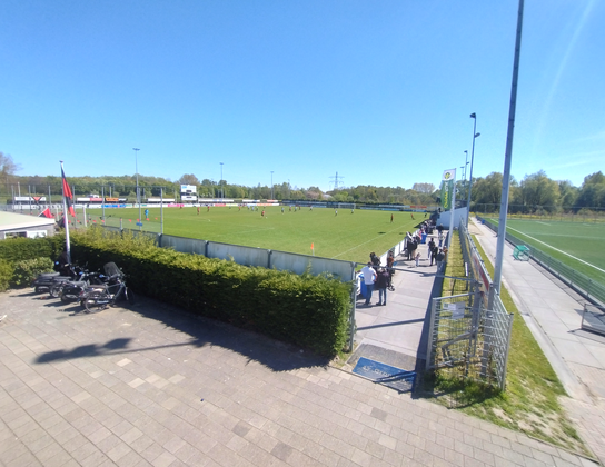 Voetbalwedstrijd op het sportpark van een Delftse sportclub die Van Gulden Makelaardij sponsort, met toeschouwers langs de lijn